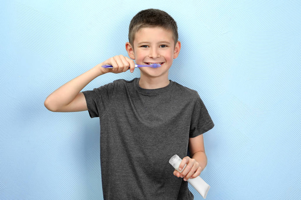Cute little boy cleaning teeth on color background - Фото, изображение