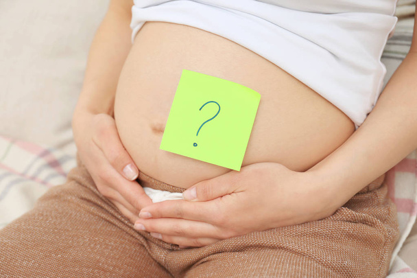 Pregnant woman with paper sticker on tummy, closeup. Concept of choosing baby name - Foto, Imagem