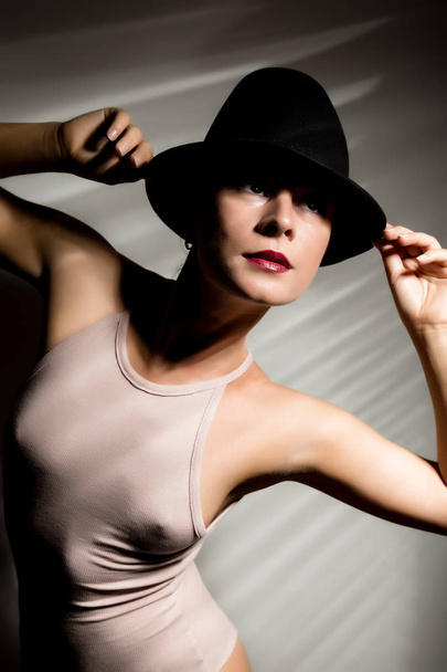 сексуальна жінка в бежевому купальнику і чорний капелюх в тіньовій смузі
 - Фото, зображення