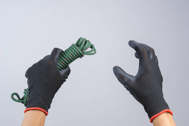 Hand trägt dunklen Handschuh und hält grüne Fallschirmschnur aus Nylo - Foto, Bild