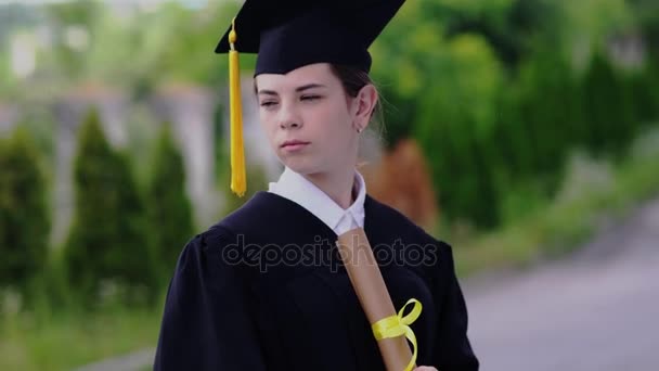 Εξωτερική σκηνή της όμορφης φοιτήτριας αποφοίτηση ντυμένος στο κύπελλο και φόρεμα. - Πλάνα, βίντεο
