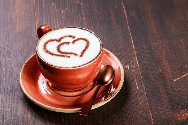 A cup of coffee with heart pattern on wooden background. Latte art - Photo, Image