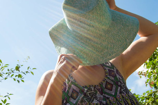 Женщина закрывает лицо от солнца его шляпой.
 - Фото, изображение