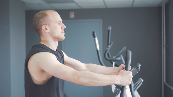 Young attractive man cycling on the exercise bike in the gym - Materiał filmowy, wideo