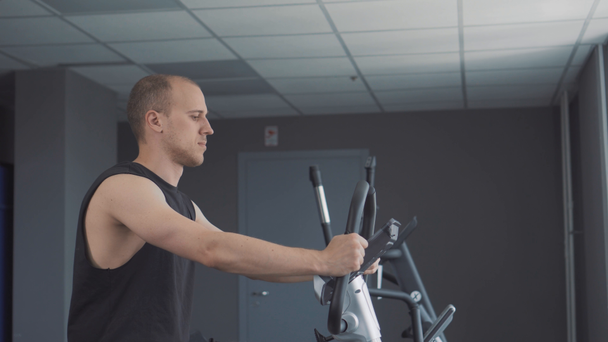 Young attractive man cycling on the exercise bike in the gym - Filmagem, Vídeo