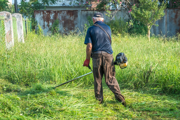 O jardineiro cortando grama por cortador de grama
 - Foto, Imagem