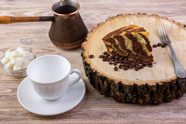 明るい木製の背景に角砂糖をコーヒー カップ、フォーク、コーヒー豆、ボウルと木の切り株にチョコレート ケーキ - 写真・画像