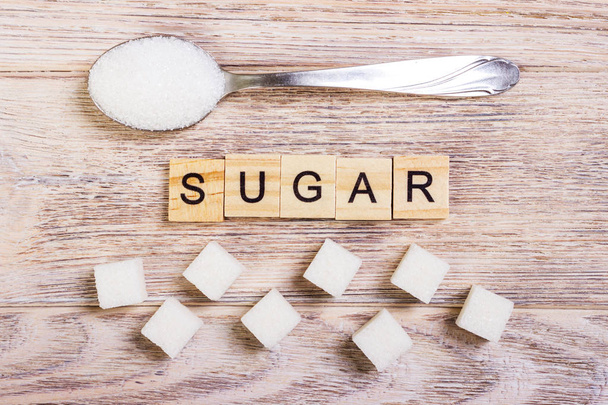 Rafine şeker ve şeker yığının üstüne bir kaşık ile diyabet blok ahşap harfler - Fotoğraf, Görsel