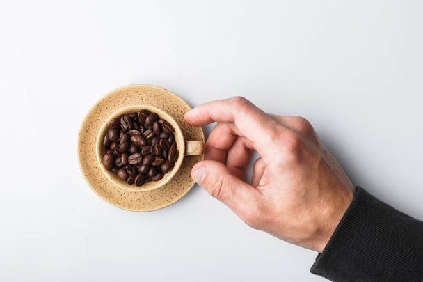 Hand stretching to a cup of coffee on a white background, poured - Photo, Image