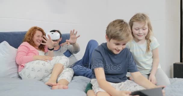 Father Trying Virtual Reality Glasses While Son Using Tablet In Bedroom, Family Together At Home - Кадри, відео