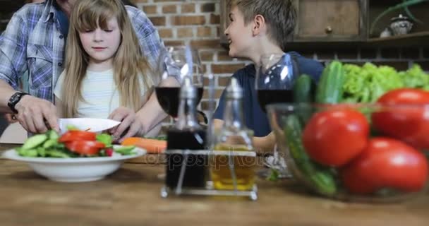 Family Cooking Together In Kitchen Parents With Two Kids Preparing Food At Home Talking Chopping Vegetables For Salad - Filmati, video