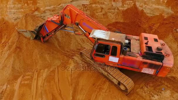 Ein orangefarbener Raupenbagger steht auf einer Sandmine. Bergbaubagger - Filmmaterial, Video