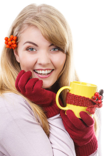 Happy girl with rowan in hair wearing woolen gloves and holding cup of tea wrapped scarf - Photo, Image