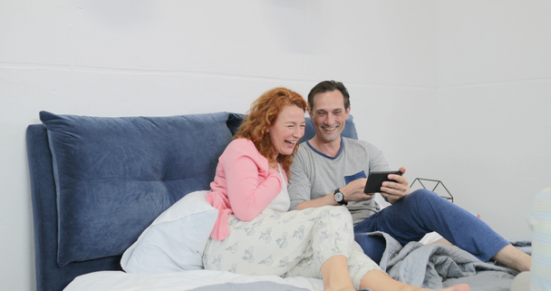 Couple adulte utilisant un téléphone intelligent cellulaire allongé au lit sur des enfants jouant ensemble famille dans la chambre à coucher
 - Séquence, vidéo