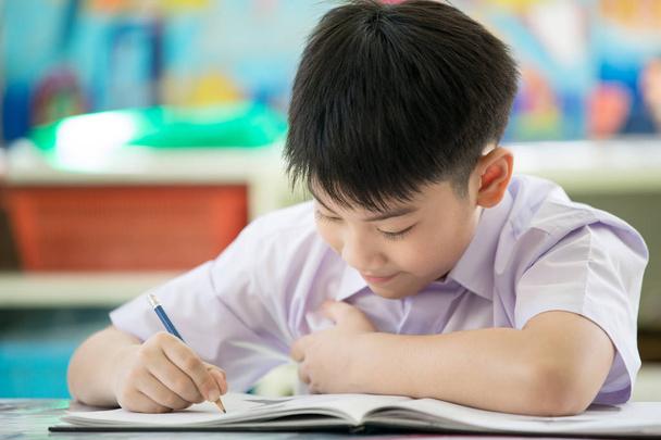 Cabeza tiro Retrato de feliz asiático lindo niño haciendo tarea con
 - Foto, imagen