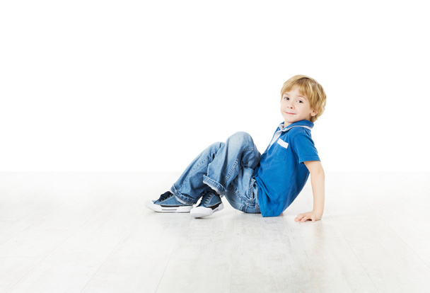 Smiling little boy sitting down on floor - Фото, зображення