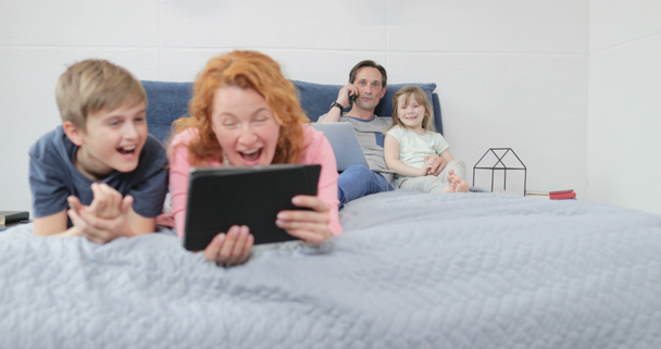 Padre abrazando a la pequeña hija mientras habla por teléfono feliz familia sonriente sentados juntos en la cama
 - Metraje, vídeo