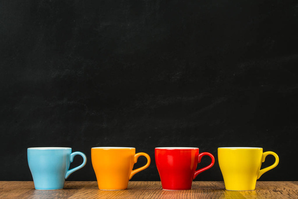 four colored coffee cups on the vintage wood - Фото, изображение
