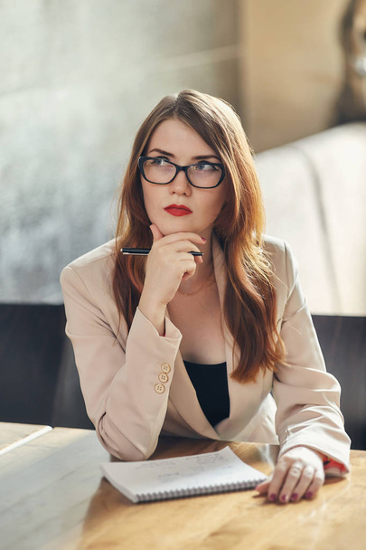 Young caucasian businesswoman with notebook. Woman in glasses in a cafe - Fotó, kép