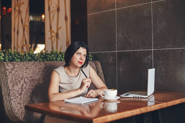 Young caucasian businesswoman with laptop and notebook. Woman in cafe - Фото, зображення