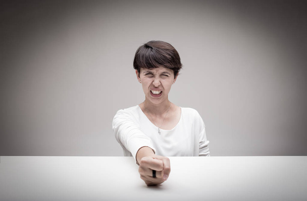 сердитая женщина бьет кулаком по столу
 - Фото, изображение