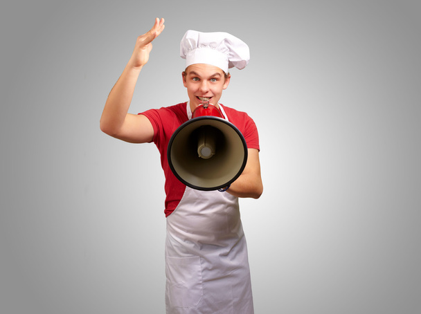 portrait de l'homme cuisinier heureux criant en utilisant mégaphone sur ba gris
 - Photo, image