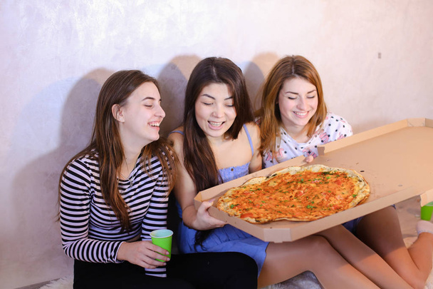 Chicas lindas fresco pasar tiempo y disfrutar de la pizza, sentarse en el suelo en bergantín
 - Foto, imagen