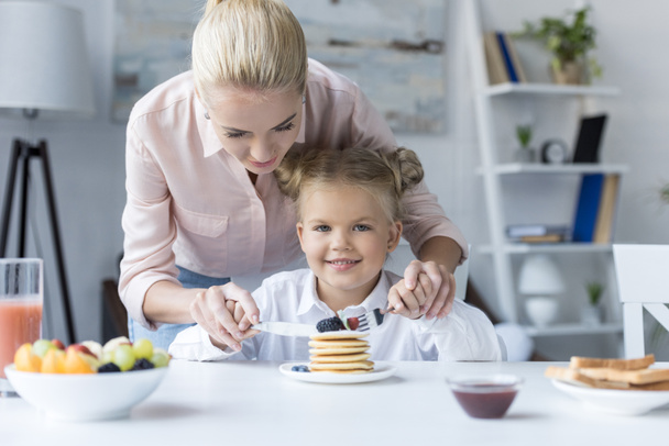 mother and daughter eating pancakes - 写真・画像