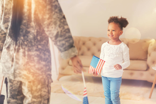 Little girl standing in front of her mother with American flag - Fotó, kép