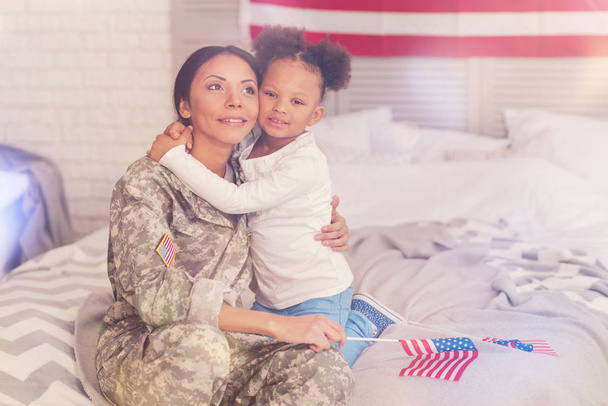 Military mother and daughter bonding to each other on bed - Foto, afbeelding