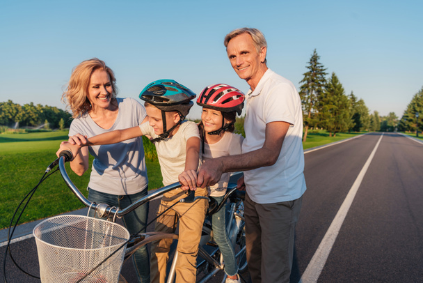 бабушки и дедушки помогают детям ездить на велосипеде
 - Фото, изображение