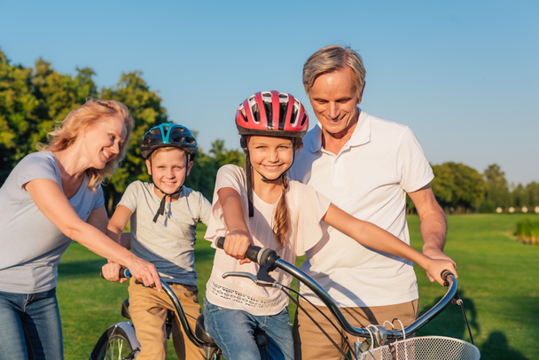 grandparents helping children ride bicycle - Foto, immagini