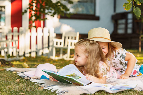 Cute Little Blond dziewczyny czytanie książki poza na trawie - Zdjęcie, obraz