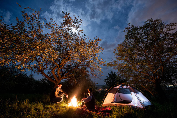 пара туристов у костра возле палатки
 - Фото, изображение