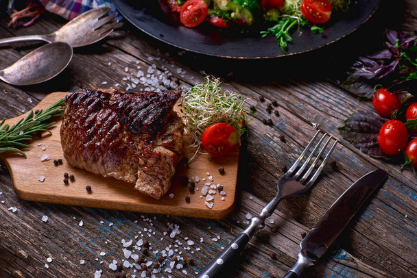 Bovenaanzicht van zout, kleurrijke groenten en hartige sauzen geserveerd met gegrilde steak op een rustieke houten teller in een land steakhouse. Close-up - Foto, afbeelding