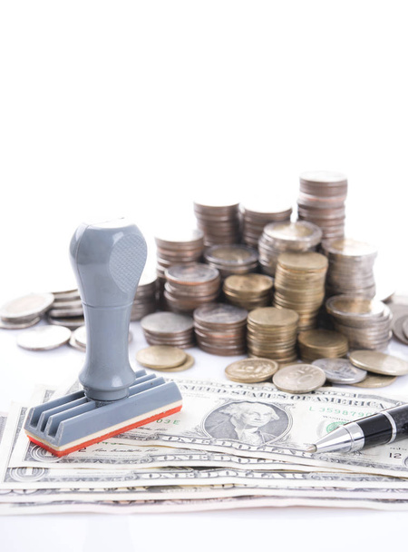 Резиновый штамп, ручка и куча монет с долларовыми купюрами
 - Фото, изображение