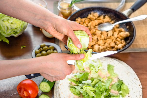Готувати швидку їжу. Руки готують обгортання тортильї з курячим та овочевим салатом, начинкою з гіроскопів для шашлику
. - Фото, зображення