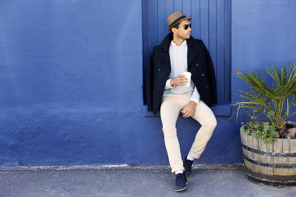 Guy sitting against blue wall - Photo, image