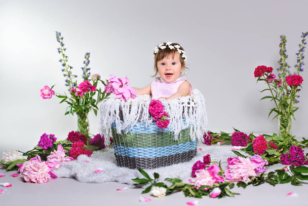 happy a small child sits with a flower, grey background. - Φωτογραφία, εικόνα