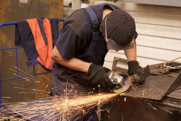 Nahaufnahme eines Arbeiters, der Metall mit dem Schleifer schneidet. Funken beim Eisenschleifen. - Foto, Bild