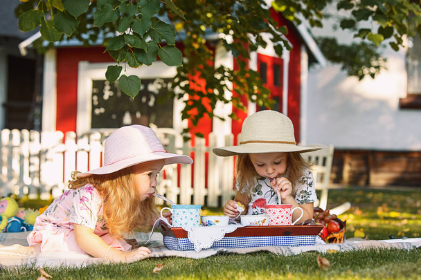 Two little girls sitting on green grass - Fotografie, Obrázek