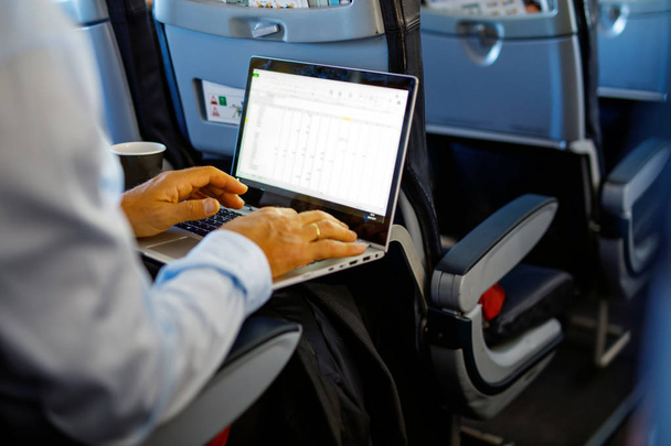 Jeune homme d'affaires méconnaissable avec un cahier assis dans un avion
 - Photo, image