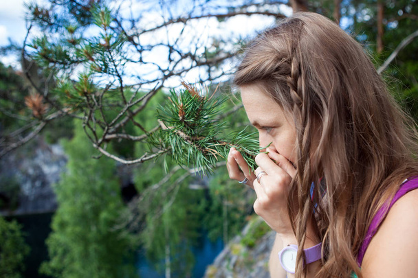 blond meisje genieten van de geur van dennennaalden in het bos - Foto, afbeelding