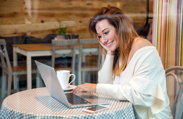 Ділова жінка, що працює з ноутбуком та мобільним телефоном у кафе, концепція фрілансу
 - Фото, зображення
