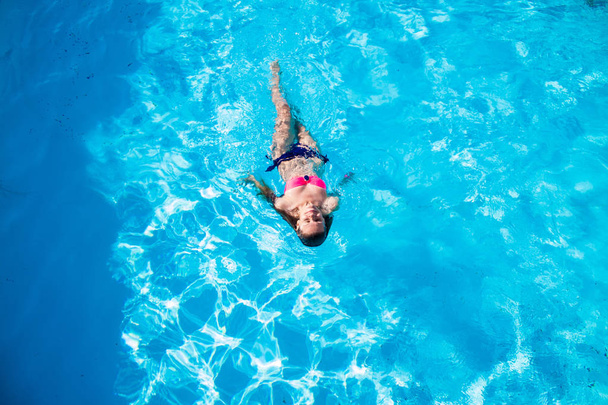 Woman on the back in the swimming pool, top view - Foto, imagen