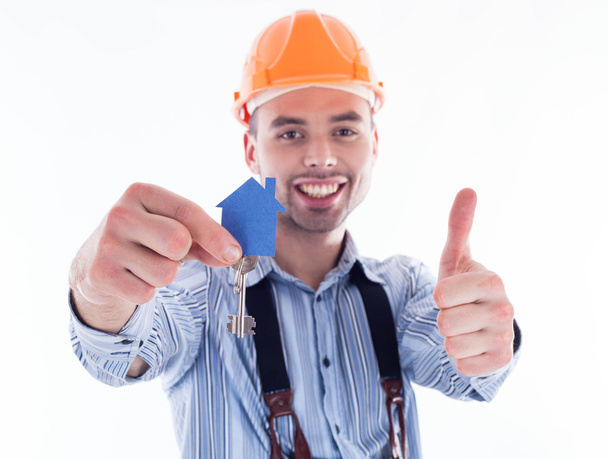 A builder man holding a key and a paper house. - Foto, Imagen