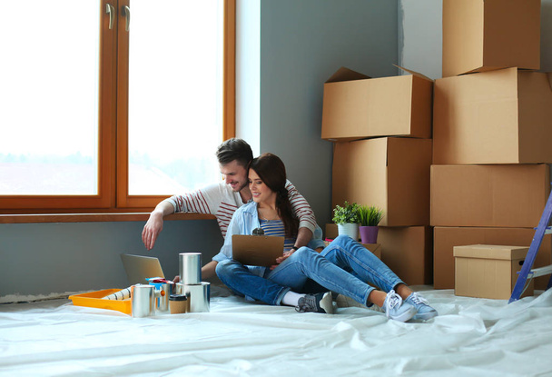 Young couple sitting on the floor of their new apartment - 写真・画像