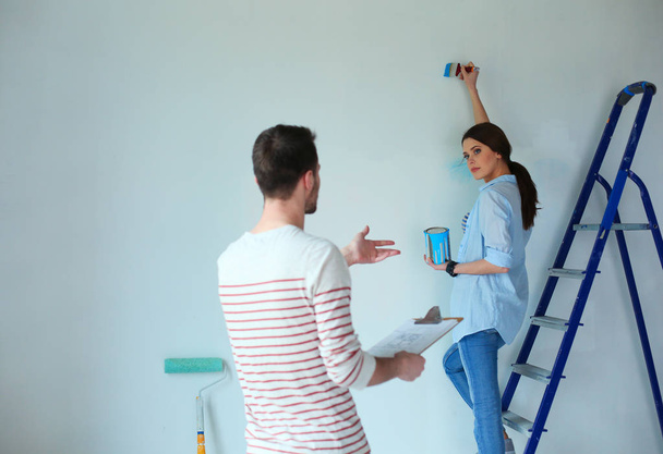 Portrait of happy smiling young couple painting interior wall new house - Foto, Imagem