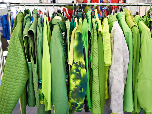 Chaquetas, chalecos y ropa de lluvia en la percha en la tienda
 - Foto, Imagen