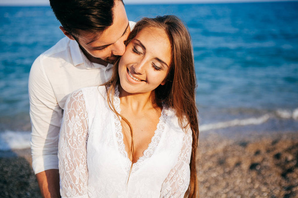 Happy young couple on the beach in love embracing and hugging smiling - Foto, Bild